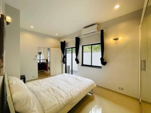 Bright bedroom with white walls, large bed, air conditioner, and wardrobe