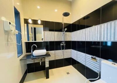 Modern bathroom with black and white tiled walls, shower, sink, and toilet