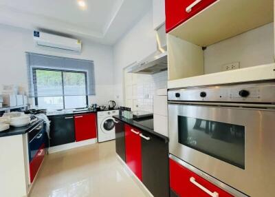 Modern kitchen with red and black cabinetry, equipped with appliances.