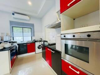 Modern kitchen with red and black cabinetry, equipped with appliances.