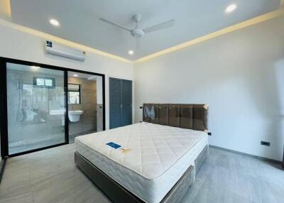 Modern bedroom with attached bathroom, a large bed, sliding glass doors, and installed air conditioning.