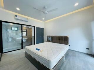 Modern bedroom with attached bathroom, a large bed, sliding glass doors, and installed air conditioning.