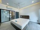 Modern bedroom with attached bathroom, a large bed, sliding glass doors, and installed air conditioning.