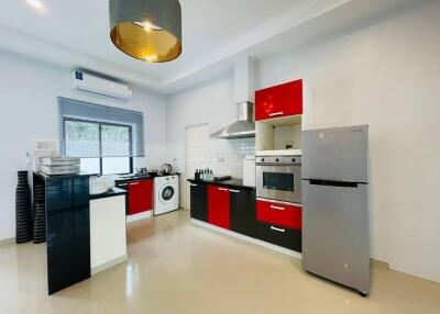 Modern kitchen with red and black cabinets, stainless steel appliances, and white countertops