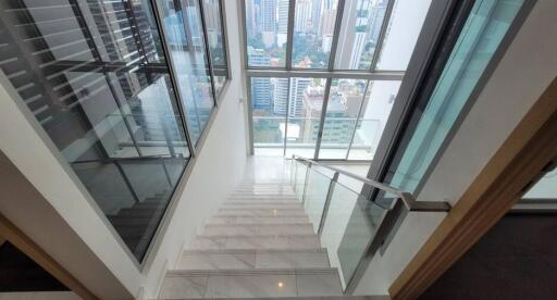 View of a stairway with glass railings and cityscape through large windows