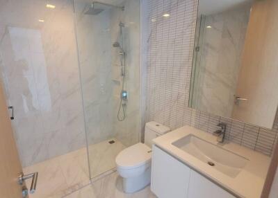 Modern bathroom with glass-enclosed shower and white fixtures.