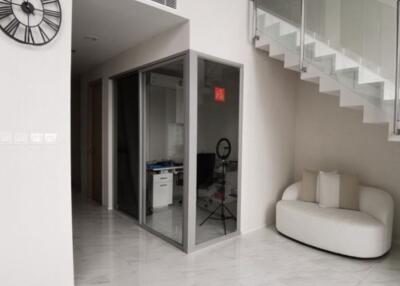 Modern living room area with a staircase and glass office enclosure