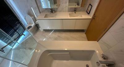 Modern bathroom with double sinks, bathtub, shower, and toilet