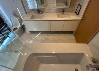 Modern bathroom with double sinks, bathtub, and toilet