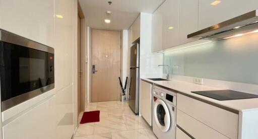 Modern kitchen with white cabinets, built-in appliances, and washing machine.