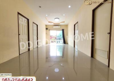 A spacious hallway with glossy tiled floors, multiple doors, and a view towards a balcony.