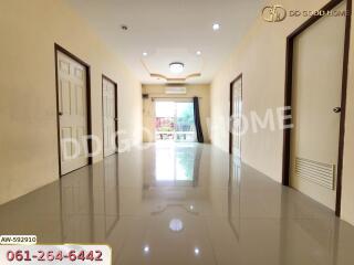 A spacious hallway with glossy tiled floors, multiple doors, and a view towards a balcony.