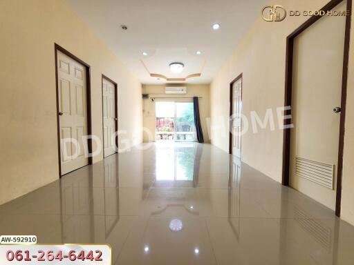A spacious hallway with glossy tiled floors, multiple doors, and a view towards a balcony.