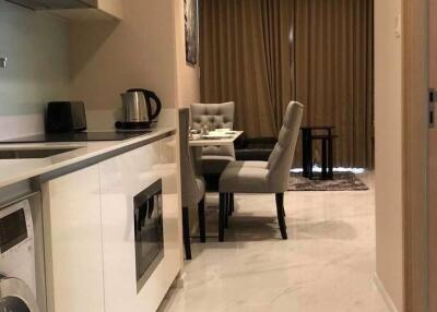 Modern kitchen and dining area with white cabinetry, appliances, and dining table with cushioned chairs