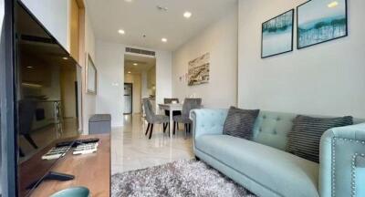 Modern living room featuring a comfortable green couch, dining table, and wall art