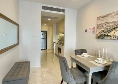 Modern dining area adjacent to the kitchen in a contemporary apartment with a large mirror and a cityscape painting.