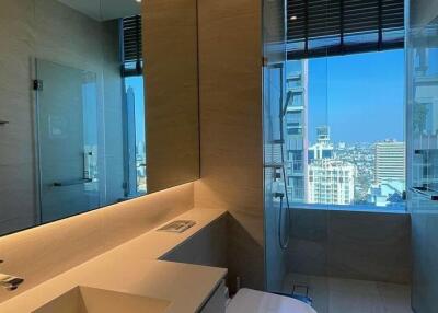 Modern bathroom with city view, large mirror, and glass shower.