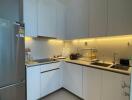 Modern kitchen with stainless steel refrigerator and under-cabinet lighting