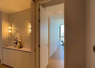 A hallway leading to a room with a glass door and a small Christmas tree decoration on a cabinet