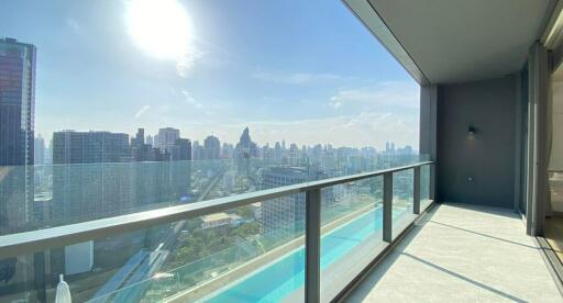 Spacious balcony with glass railing offering city skyline views on a sunny day