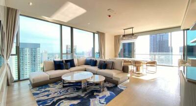 Spacious living room with a large sectional sofa, glass coffee tables, and a view of the cityscape.