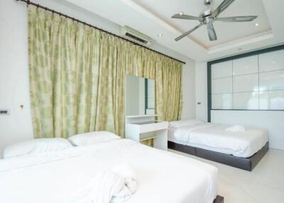 Spacious bedroom with two beds, ceiling fan, and large window with curtains
