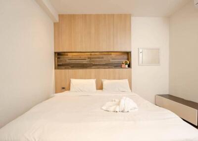 Modern minimalist bedroom with double bed, wooden headboard and accent wall
