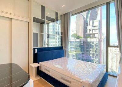 Spacious bedroom with large windows overlooking city view and modern furnishings