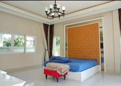 Spacious bedroom with large windows, comfy bed and chandelier
