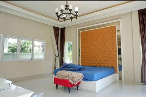 Spacious bedroom with large windows, comfy bed and chandelier