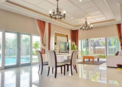 Spacious and modern living room with large windows, chandeliers, and a view of the pool