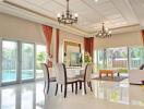 Spacious and modern living room with large windows, chandeliers, and a view of the pool