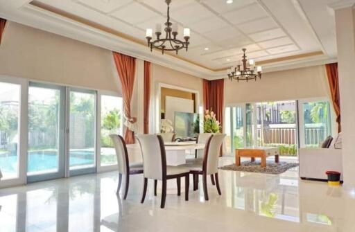 Spacious and modern living room with large windows, chandeliers, and a view of the pool