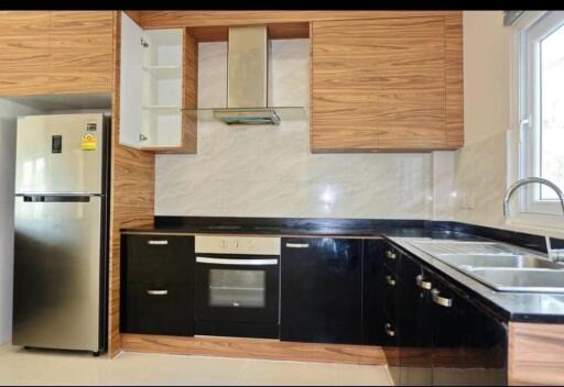 Modern kitchen with wooden and black cabinets, stainless steel appliances, and a large window