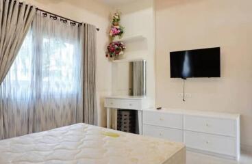 Bedroom with a window, curtains, bed, vanity table, and wall-mounted TV