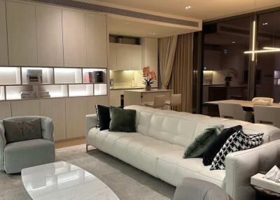Modern living room with dining area, featuring a sleek white sofa, armchair, and contemporary decor