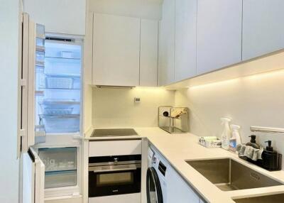 Modern white kitchen with open refrigerator, built-in oven, and washing machine