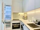 Modern white kitchen with open refrigerator, built-in oven, and washing machine