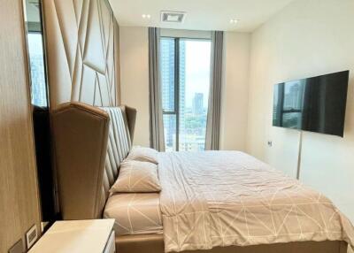 Modern bedroom with large bed, wall-mounted TV, and floor-to-ceiling window