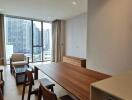 Modern living room with a city view featuring a wooden dining table, chairs, sofa, and large windows