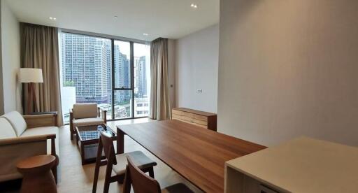 Modern living room with a city view featuring a wooden dining table, chairs, sofa, and large windows