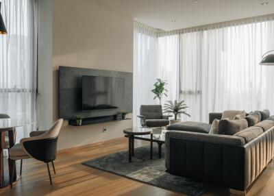 Modern living room with large windows, curtains, and cozy furniture