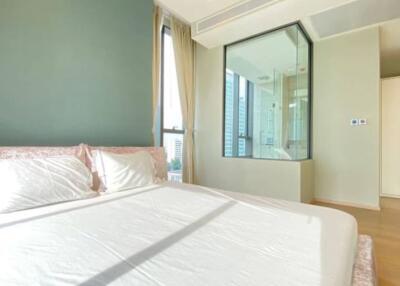 Bedroom with large bed, green accent wall, and glass shower area