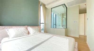 Bedroom with large bed, green accent wall, and glass shower area