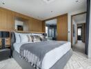 Modern bedroom with wooden panel accent wall, bed with gray and white bedding, and nightstands