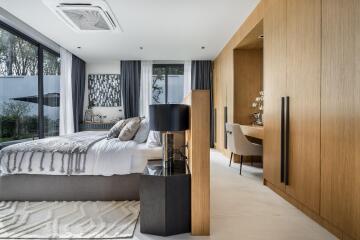Spacious modern bedroom with large windows, a work desk, and built-in wardrobe