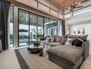 Modern living room with large glass doors, spacious sofa, and view of the outdoor pool