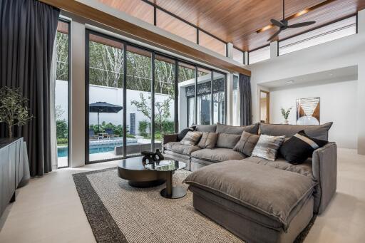 Modern living room with large glass doors, spacious sofa, and view of the outdoor pool