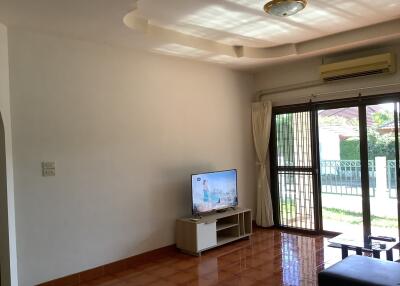 Spacious living room with television and large window with garden view.