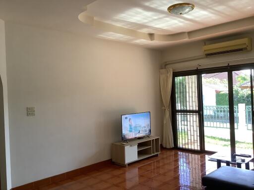 Spacious living room with television and large window with garden view.